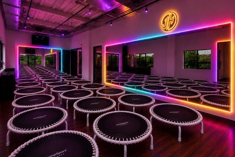 JumpHaus studio with rows of rebounders and rainbow neon mirrors
